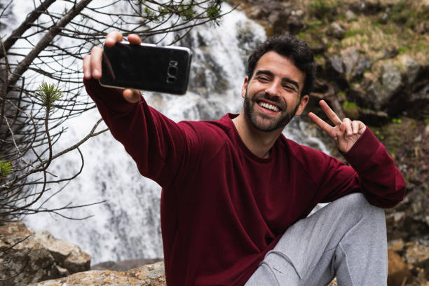 istock Delighted traveling man taking selfie against waterfall 2185206467