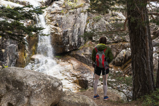 istock Unrecognizable female hiker standing near waterfall in mountainous forest 2185206477