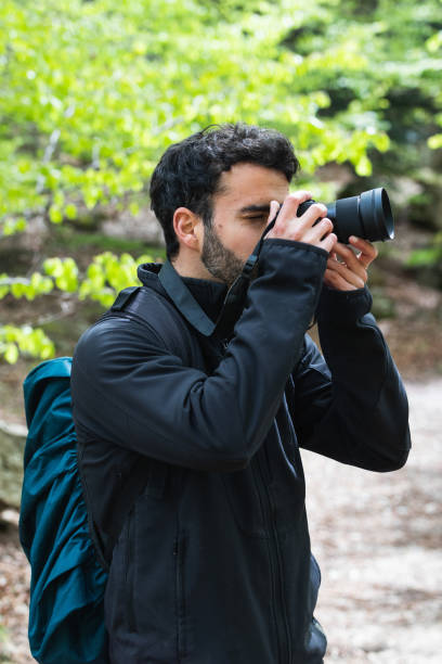 istock Traveling man taking photo on camera in woods 2185206736