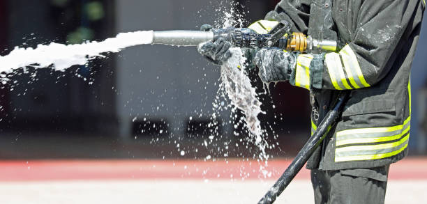 istock firefighter spraying foam agent from a hose to put out a fire while wearing protective gear 2185208211