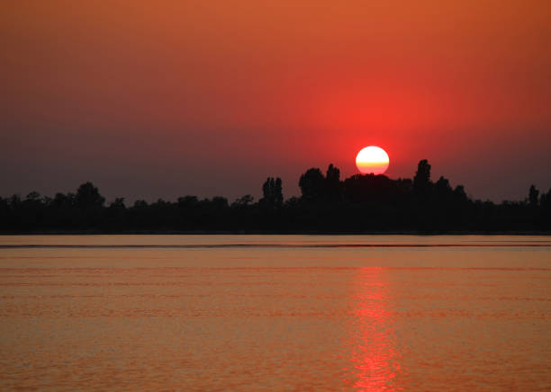 red sun setting over island reflecting on sea water