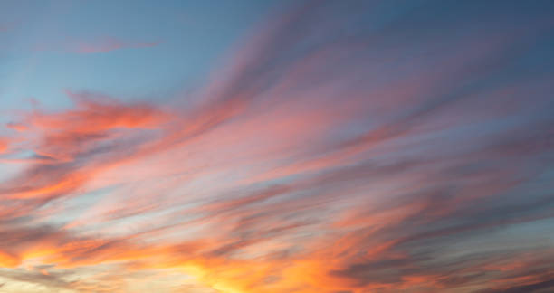 istock Sunset sky background with golden orange clouds on blue 2185209583