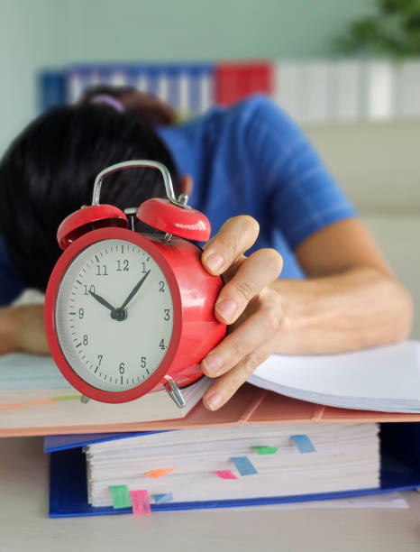 istock Tired office worker struggling to meet deadline and looking at alarm clock 2185209759