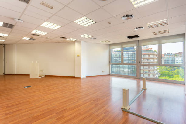 istock Empty office and fluorescent lamps on the ceiling in need of repair and replacement. Bright office space for rent. Light brown parquet and large panoramic windows in an empty abandoned office. 2185209767
