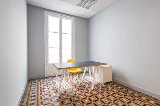 istock An empty room with gray smooth walls, doors leading to terrace. Floor is made of patterned marble tiles. There is table with gray top a yellow plastic chair with wooden legs in room. 2185211548
