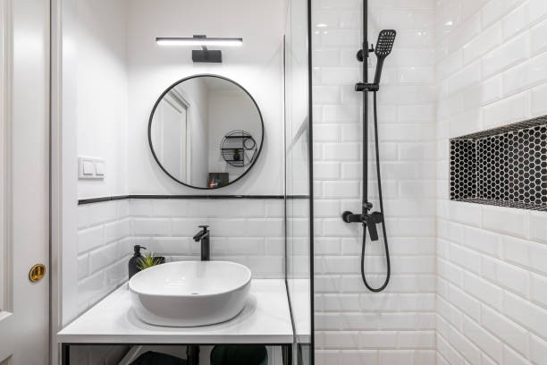 istock Modern bathroom in black and white style with high-quality expensive fittings. White brick walls and sink on countertop are matched with black faucets framed in mirror and decorative elements. 2185212491