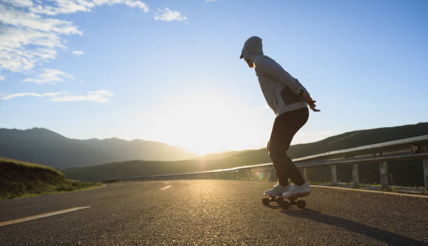 istock Skateboarder skateboarding on the sunset mountain top road 2185214179