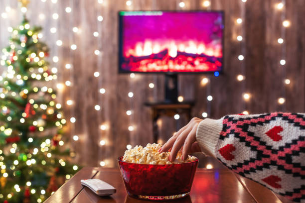 istock Christmas eve. Alone woman eating popcorn, watching tv, switching channels using remote control. Home cinema. Cropped, close up 2185215263
