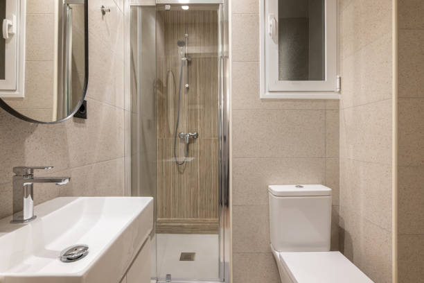 istock Beautiful fresh and comfortable bathroom for water procedures, morning and evening exercise. Room in beige tones with large sink, beautiful mirror, glass shower and white toilet. 2185217885