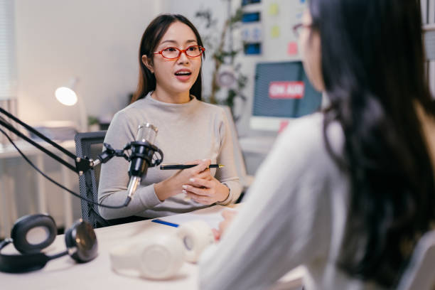istock Two young female podcasters are recording a podcast in a professional studio, engaging in a discussion while using a microphone and headphones 2185219014
