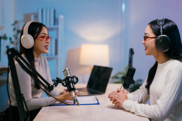istock Two young female podcasters are recording an episode in a professional studio, using headphones and microphones, with a laptop on the table 2185219036