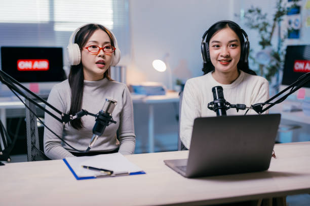 istock Two young asian women recording a podcast in a modern studio, fully immersed in their work, showcasing the power of technology and teamwork in content creation 2185219072