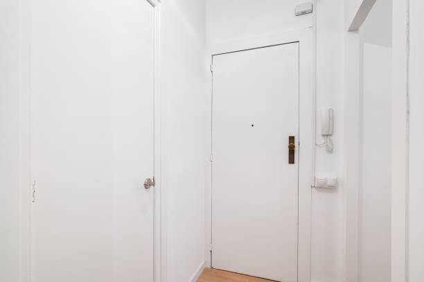 istock White front door to apartment with intercom on wall. There is peephole in door for observing what is happening outside. Door lock protects the apartment from the entry of unauthorized persons 2185219104