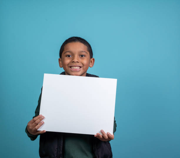 istock Elementery school hispanic boy looking at the camera holding a sign 2185219495