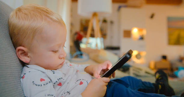 istock Baby Boy using Mobile Phone on Sofa at Home 2185221047