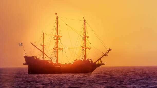 istock Silhouette of pirate ship sailing at sunset backlit by sunlight 2185222310