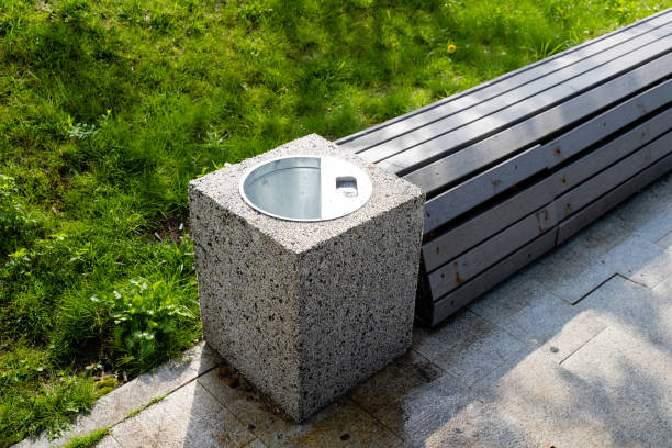 istock In a serene park, there is a concrete trash can positioned conveniently next to a sturdy wooden bench, providing a perfect spot for visitors to sit and enjoy the tranquility of nature 2185228284