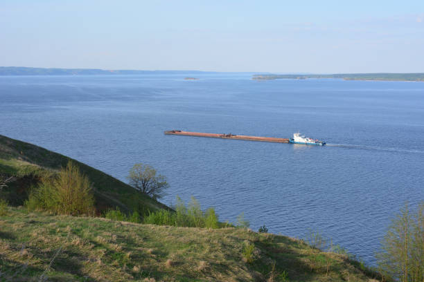 a large ship is in the water near a hill