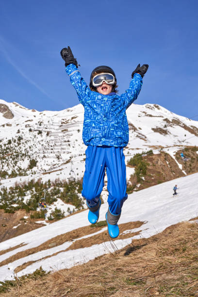 A snowboarder in red gear performs a mid-air jump on a snow-covered mountain slope. The scene is set against a backdrop of foggy conditions and tall, snow-dusted trees, showcasing the exhilaration of winter sports and the beauty of the winter landscape.
