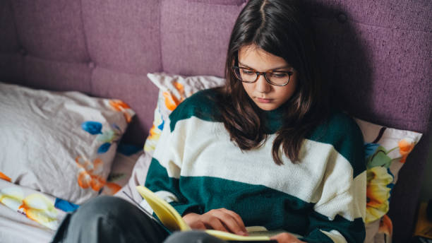 istock Girl reading a book at home 2185229444