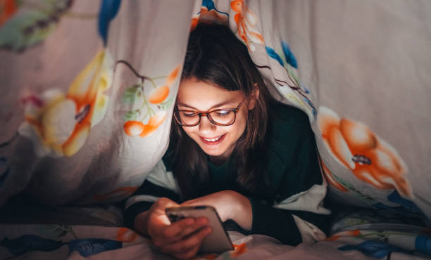 Girl using smart phone under blanket Girl using smart phone under blanket Dating girl stock pictures, royalty-free photos & images