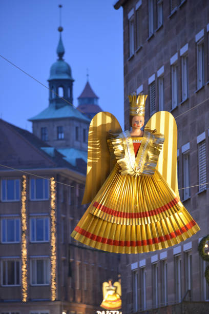 A close-up of hanging Christmas decorations at Barfüsserplatz, Basel, Switzerland, showcasing a traditional angel figurine and colorful ornaments in a festive setting.