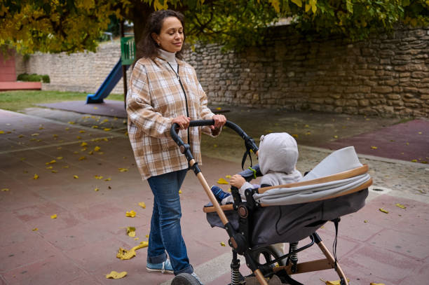 istock Mother strolling with baby in a stroller through a park 2185233715