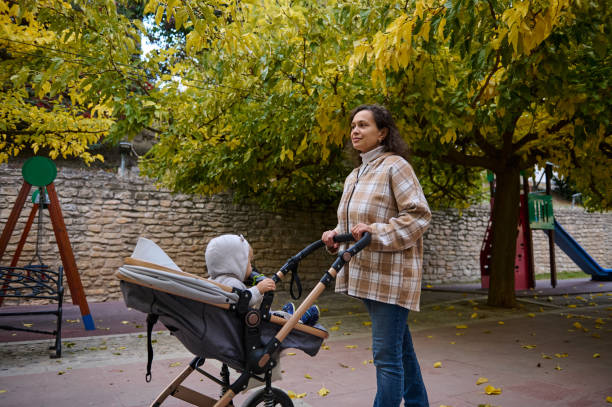 istock Mother pushing stroller in serene autumn park setting 2185233740