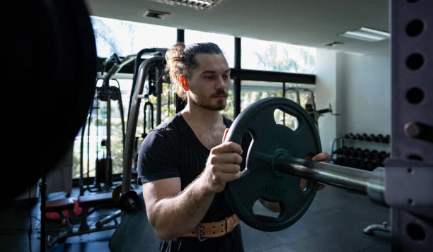 istock Caucasian muscular body builder sport man is practice weight training on barbell for core muscle inside the gym with dark background for exercising and workout 2185235473