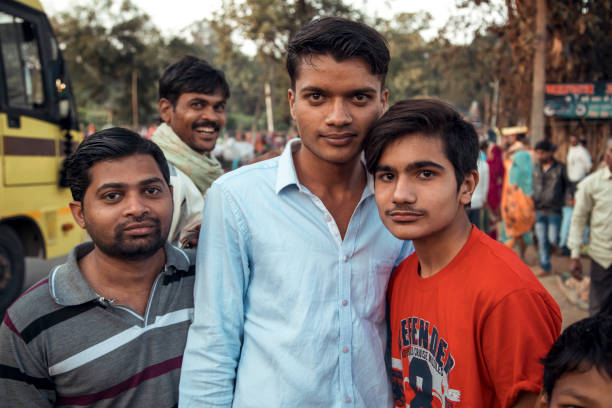 Padhar, India - A group of young men stands together in the bustling countryside of Maharashtra, smiling at the camera as the lively surroundings showcase local life and culture.