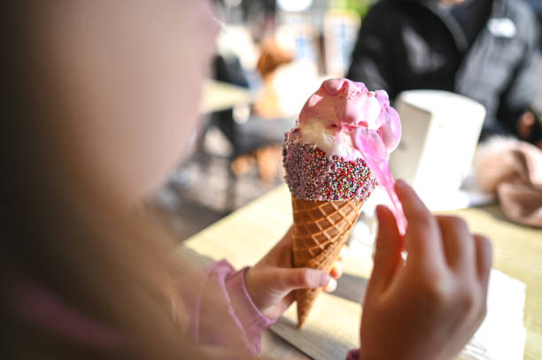 Child eating big ice cream cone close up.