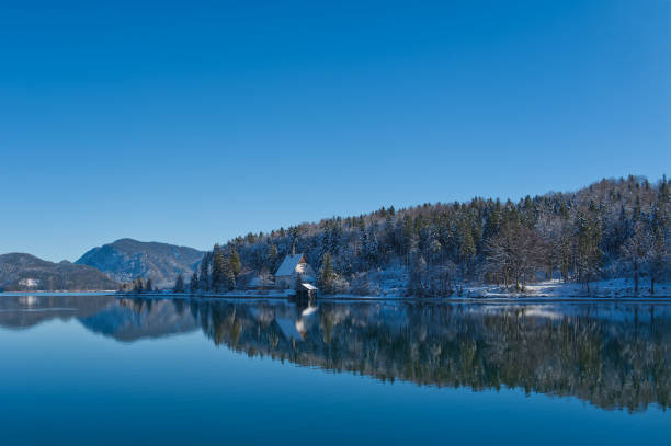Winterlandscape at a lake with mirroring, reflections and blue sky in Bavaria, central Europe