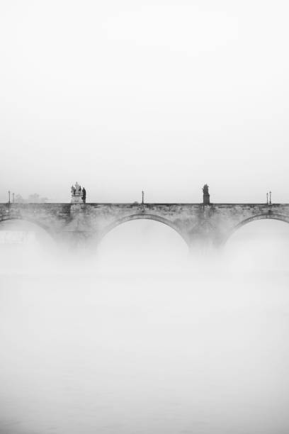 Charles bridge in Prague in the fog in the morning. Black and white. Vltava river
