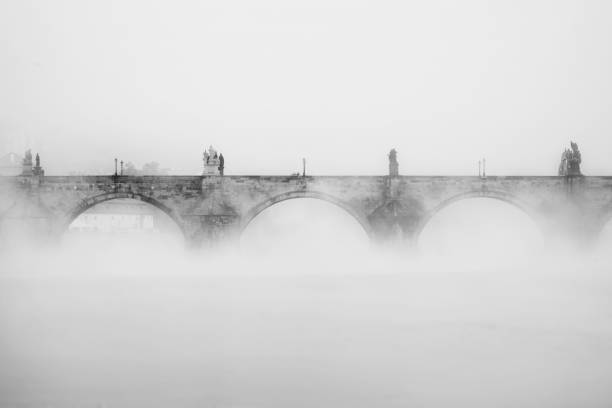 Charles bridge in Prague in the fog in the morning. Black and white. Vltava river
