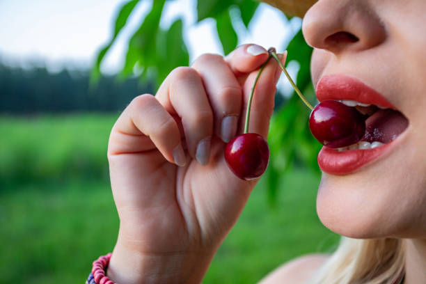 istock A woman holding a single red cherry between her teeth 2185245657