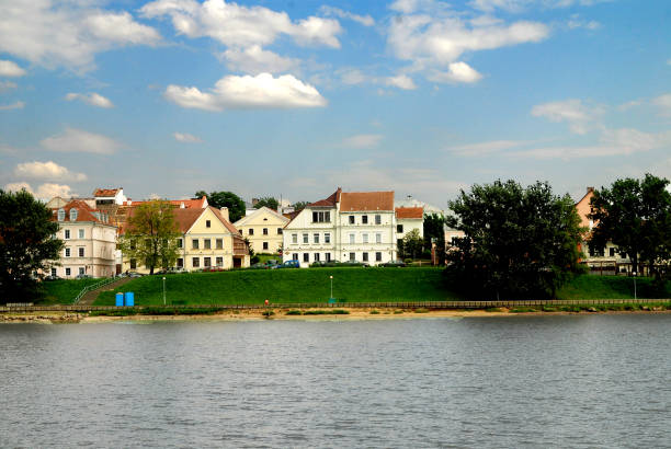 A small town with a river running through it. The houses are white and there are trees in the background. Belarus, Minsk 26.07.2010