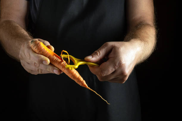 istock In a cozy kitchen illuminated by soft light, a cook peels vibrant carrots with focused hands. The orange and yellow vegetables glisten, showcasing their freshness and inviting colors 2185251768