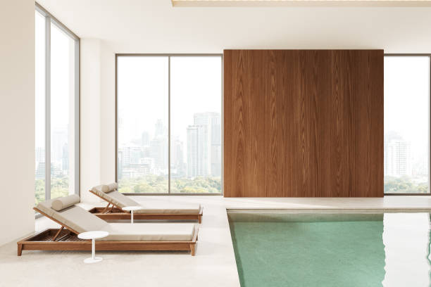 Cozy modern spa interior with loungers in row, swimming pool and panoramic window on Bangkok skyscrapers. Stylish hotel resort and relax space. 3D rendering