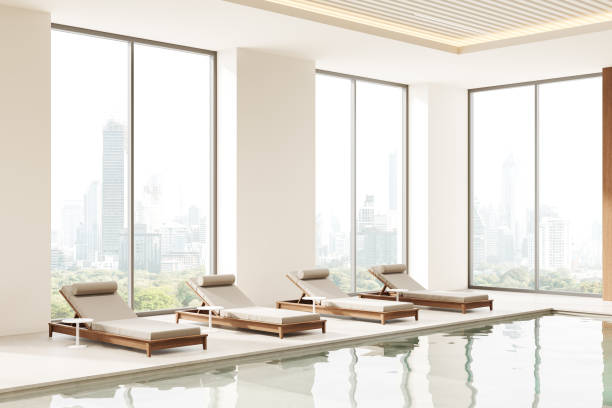 istock Luxurious indoor swimming pool with modern lounge chairs and large windows. 3D Rendering 2185252693