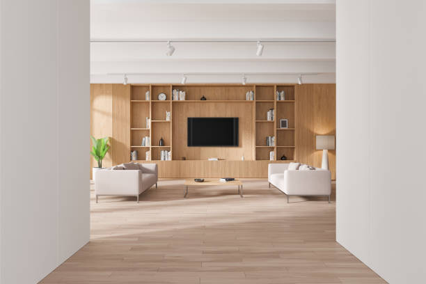 istock A modern living room featuring wooden shelves, a flat-screen TV, and beige sofas on a light wooden floor. Minimalistic design with neutral tones and natural light. 3D Rendering 2185254007