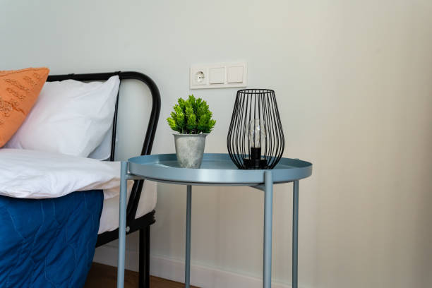 istock In the room, there is a sturdy wooden table positioned next to a soft and inviting bed, adorned with a vibrant green plant and an elegant lamp that enhances the cozy atmosphere 2185255028