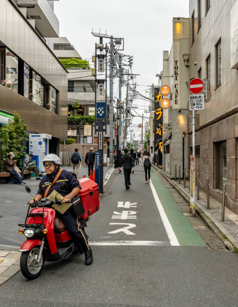 Tokyo, Japan. 29 October 2024. Delivery man on moped in Kagurazaka in Tokyo