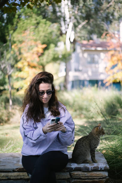 istock Woman texting in park with cat by side 2185262063