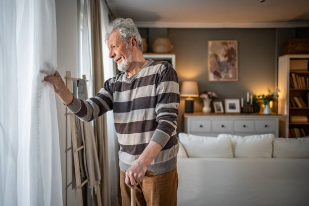 istock Peaceful everyday life, an old man stands by the window with a walking stick 2185269011