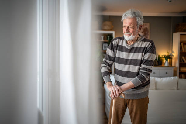 istock Peaceful everyday life, an old man stands by the window with a walking stick 2185269021