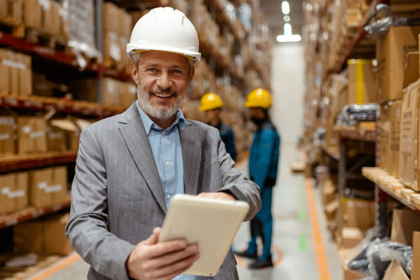istock Warehouse Manager in Industrial Setting, Reviewing Data on Tablet, Smiling at Camera 2185269077
