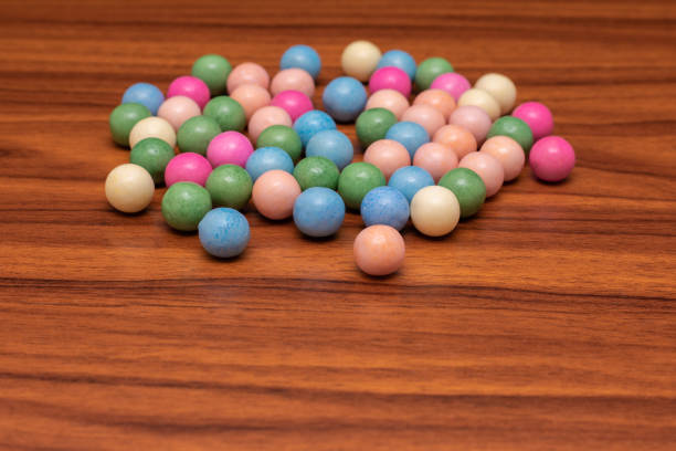 Pile of colorful candy on a wooden table. The candy is in various colors and shapes, and it looks like a fun and playful arrangement.