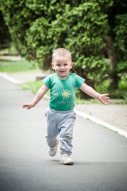 istock A cheerful young child joyfully runs along a park pathway on a sunny day, expressing happiness and carefree innocence 2185270365