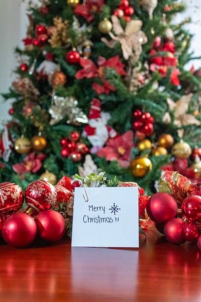 istock Christmas decoration with a handwritten note and in the background a small Christmas tree with its red and green chlorophyll decorations 2185272522