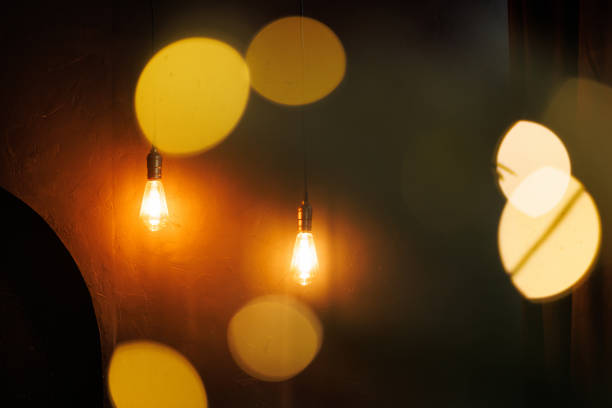 istock Two dark-light bulbs on a long cord are twined from the ceiling 2185273432